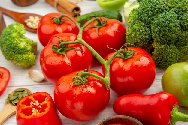 Vista inferior tomate rama brócoli cucharas de madera ajo en mesa gris