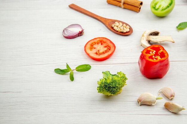 Vista inferior verduras frescas cortadas cuchara de madera setas tomate verde y rojo cebolla brócoli ajo en mesa gris lugar libre