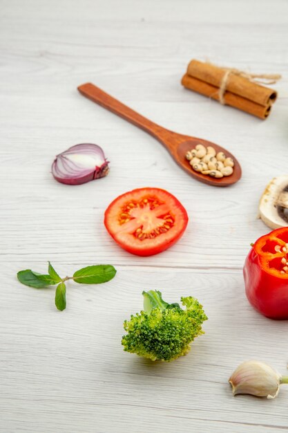 Vista inferior verduras frescas cuchara de madera hongo tomate rojo cebolla brócoli ajo hojas de menta en mesa gris