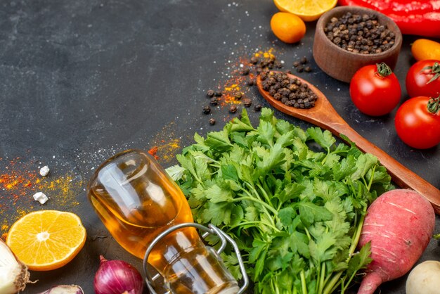 Vista inferior de verduras frescas, pimienta negra en un tazón pequeño, cuchara de madera, botella de aceite en la mesa