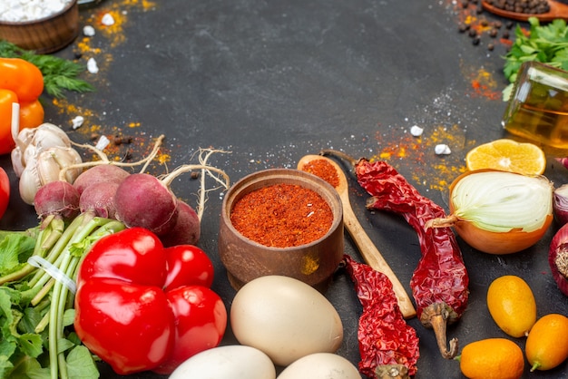 Vista inferior de verduras frescas, pimiento rojo en polvo en un tazón pequeño y una cuchara de madera, botella de aceite en el lugar de la copia de la mesa