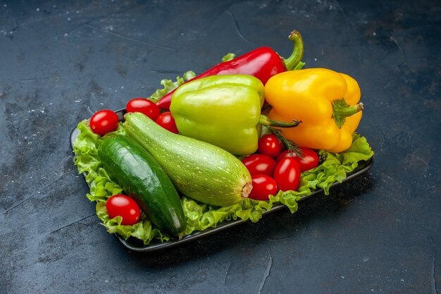 Vista inferior de verduras frescas pimientos calabacín tomates cherry lechuga pepino sobre mesa negra