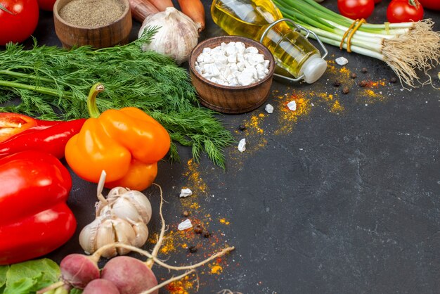 Vista inferior de verduras frescas, sal marina en un tazón pequeño, botella de aceite en el espacio libre de la mesa