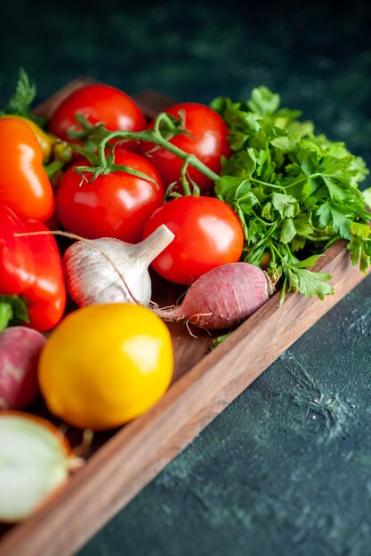 Vista inferior de verduras frescas en tablero de madera en la oscuridad