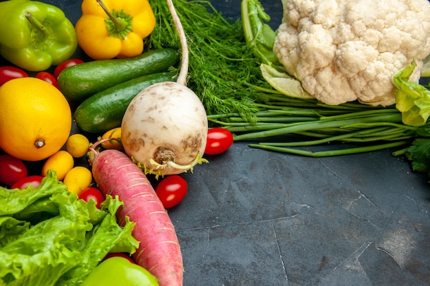 Vista inferior verduras frescas tomates cherry cumcuat coliflor rábano cebolla verde eneldo pepinos pimientos limón con espacio libre