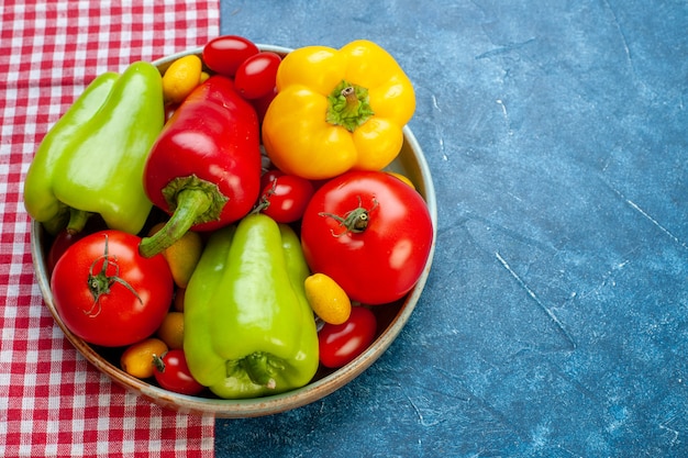 Foto gratuita vista inferior verduras frescas tomates cherry diferentes colores pimientos tomates cumcuat en plato sobre mantel a cuadros rojo y blanco sobre mesa azul espacio libre foto de stock