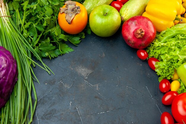 Vista inferior de verduras y frutas, tomates cherry, repollo morado, cebolla verde, perejil, lechuga, calabacín, pimiento amarillo, granada, caqui, manzana con espacio de copia