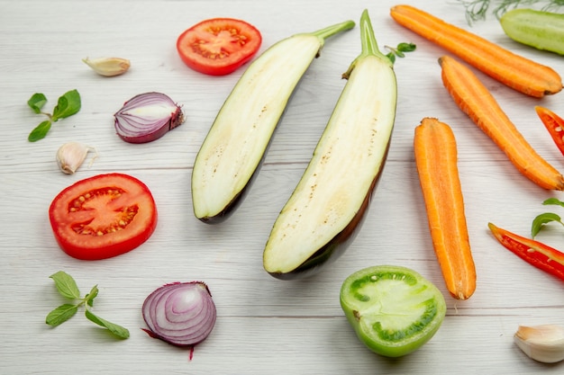 Vista inferior de verduras picadas pepino berenjena tomate zanahoria cebolla pimiento sobre mesa de madera gris