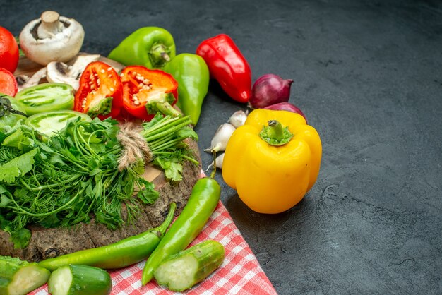 Vista inferior de verduras tomates pimientos rojos verdes en tablero rústico pimientos picantes sobre mantel en mesa negra