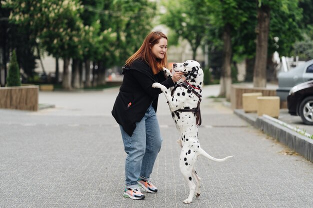 Vista de la joven mujer caucásica jugando y entrenando a su perro dálmata