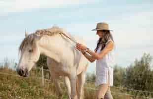 Foto gratuita vista lateral de la agricultora tejiendo el pelo de su caballo