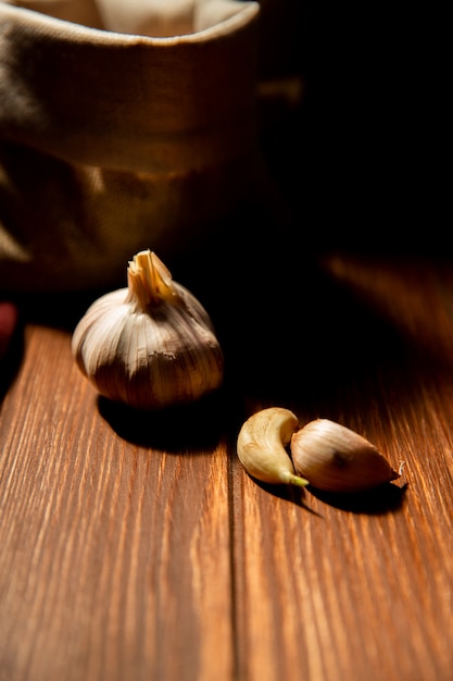 Foto gratuita vista lateral de ajo en una mesa de madera en mesa oscura