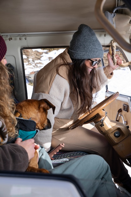 Vista lateral de las amantes femeninas con su perro durante el viaje de invierno