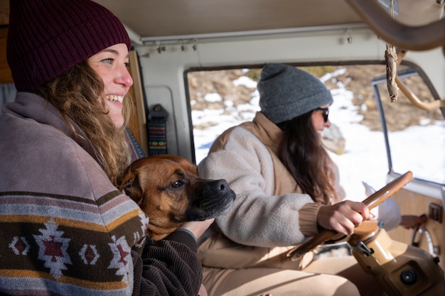 Vista lateral de las amantes femeninas con su perro durante el viaje de invierno