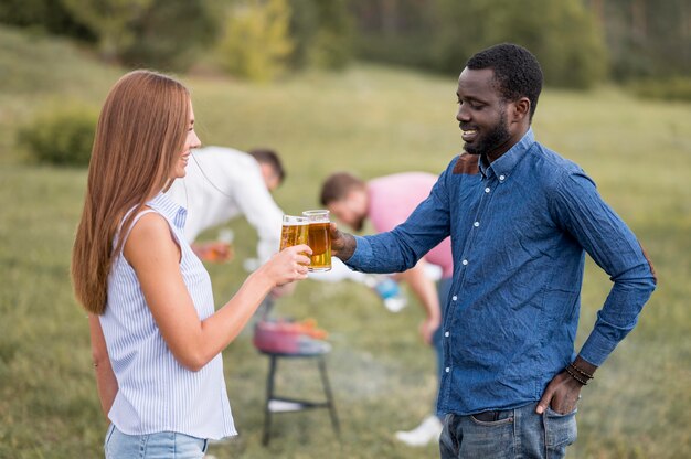 Vista lateral de amigos brindando con cerveza en una barbacoa