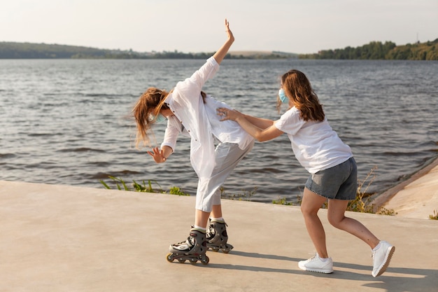 Vista lateral de amigos divirtiéndose junto al lago con patines