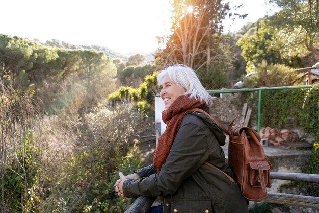 Vista lateral de una anciana admirando la naturaleza durante una caminata