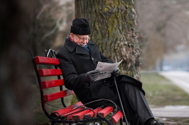Vista lateral anciano leyendo periódico