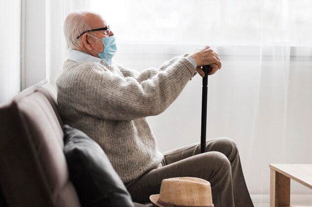 Vista lateral del anciano con máscara médica en un hogar de ancianos