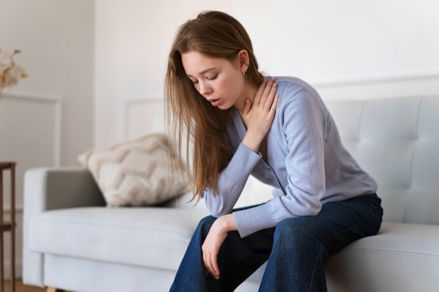 Vista lateral ansiosa mujer sentada en el sofá en casa