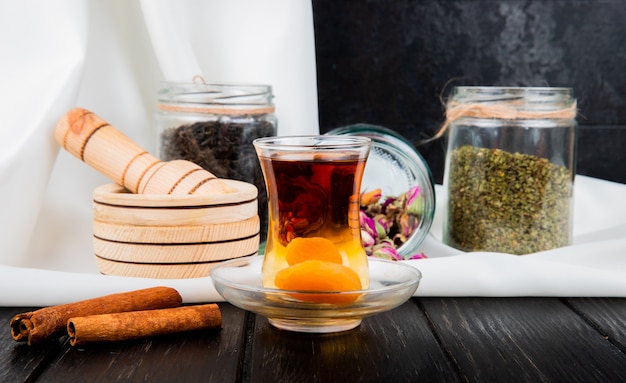 Vista lateral de armudu vaso de té con albaricoques secos y canela en rústica