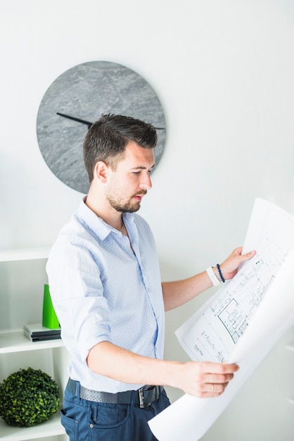 Foto gratuita vista lateral de un arquitecto masculino joven que mira el modelo