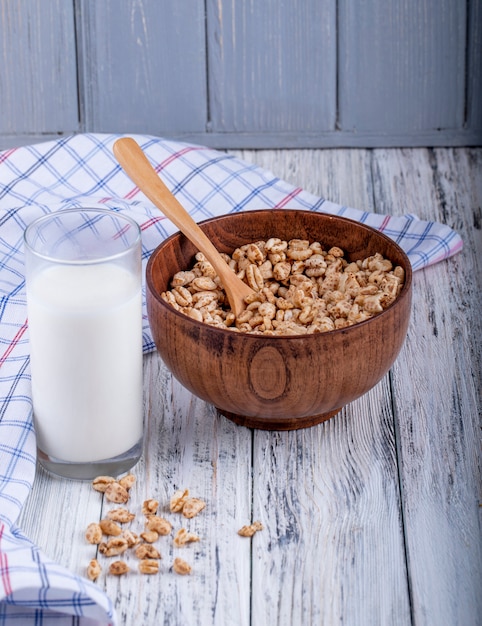 Foto gratuita vista lateral de arroz dulce inflado en caramelo en un recipiente de madera servido con un vaso de leche en rústico