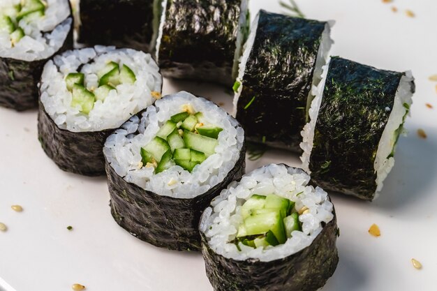 Vista lateral arroz kappa maki envuelto en algas y pepino en un plato