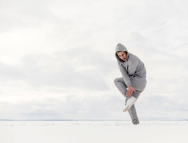 Vista lateral del artista de hip hop bailando en la nieve con espacio de copia