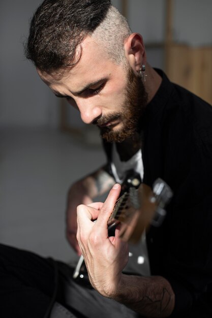 Vista lateral del artista masculino tocando la guitarra eléctrica