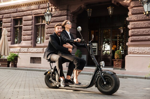 Vista lateral del asustado hombre de negocios con barba monta en moto