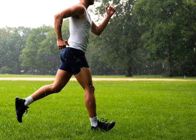 Vista lateral del atleta corriendo sobre hierba