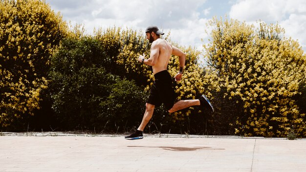 Vista lateral de un atleta masculino corriendo cerca del campo