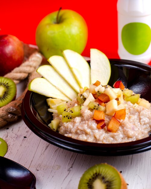 Vista lateral de avena con frutas en rodajas de manzana y kiwi