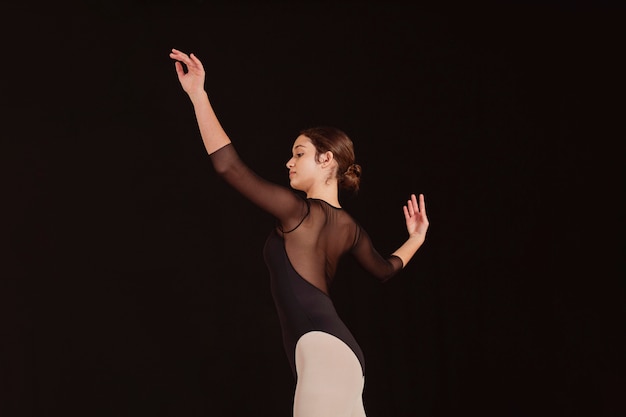 Vista lateral de la bailarina de ballet profesional practicando solo