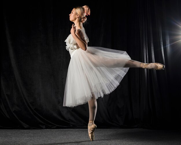Vista lateral de la bailarina posando en traje de tutú