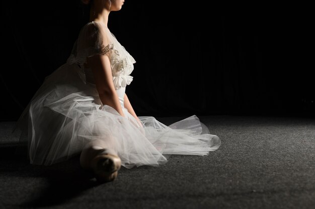 Vista lateral de la bailarina en vestido tutú haciendo una división con espacio de copia