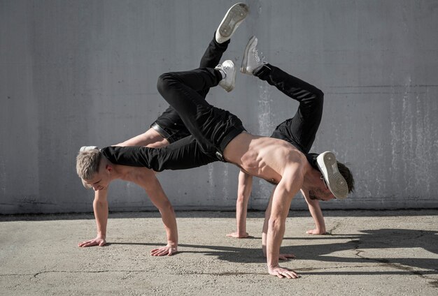 Foto gratuita vista lateral de bailarines de hip hop masculinos sin camisa ensayando juntos afuera