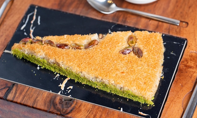 Vista lateral del baklava turco con pistacho en una tabla de madera