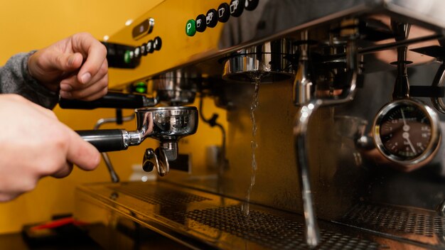 Vista lateral del barista masculino con máquina de café profesional