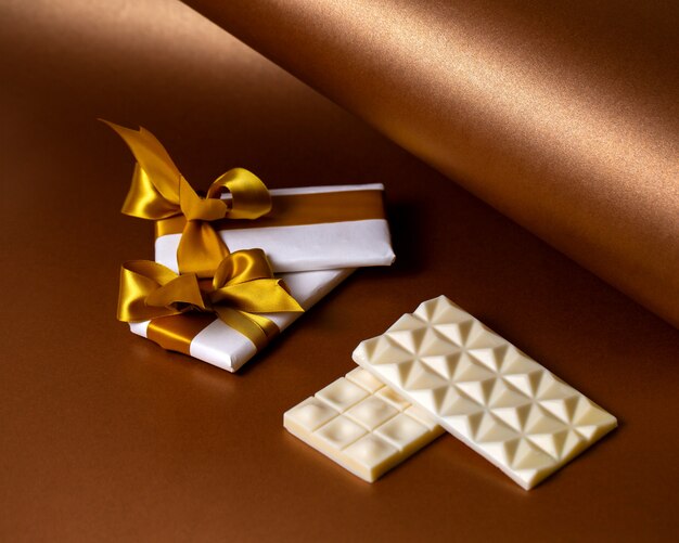 Vista lateral barras de chocolate blanco con chocolate envuelto en papel blanco con cintas doradas