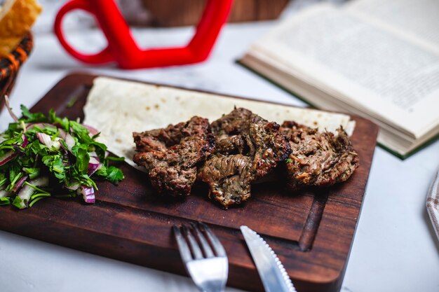 Vista lateral basturma kebab en pan de pita con cebolla y hierbas