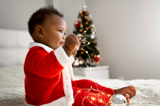 Foto gratuita vista lateral bebé jugando con luces navideñas