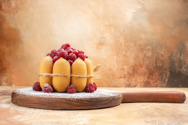 Vista lateral del bizcocho casero con frutas sobre la tabla de cortar de madera en la tabla de colores mezclados