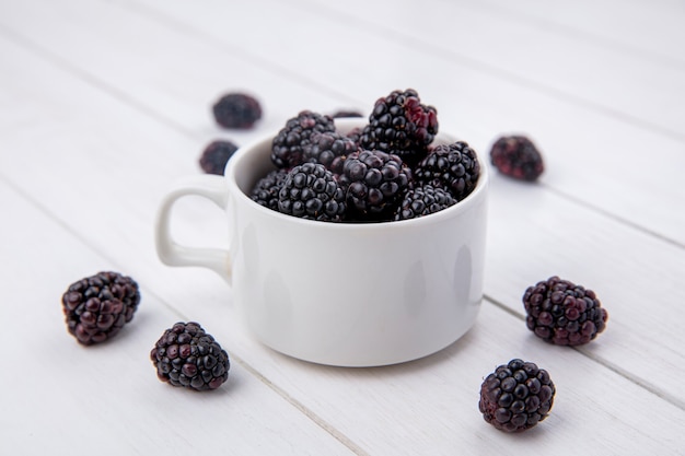 Foto gratuita vista lateral de blackberry en un vaso sobre una superficie blanca