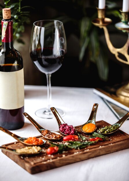 Vista lateral bocadillos en una pizarra con una botella y una copa de vino tinto