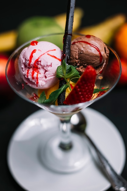 Foto gratuita vista lateral de bolas de helado de fresa y chocolate en un jarrón de vidrio decorado con menta