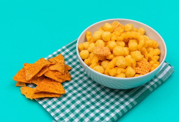 Foto gratuita vista lateral de bolas de maíz en un tazón con chips en servilleta y horizontal azul