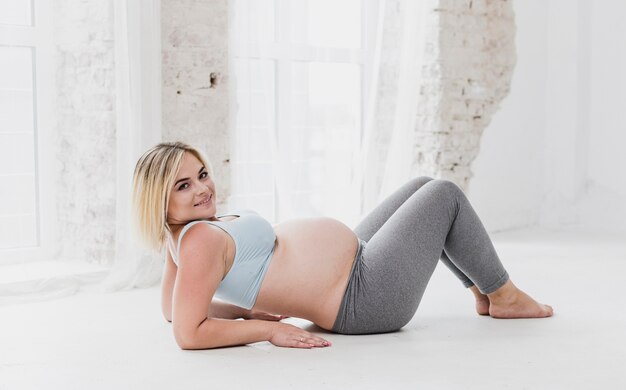 Vista lateral bonita mujer embarazada haciendo ejercicios