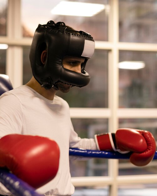 Vista lateral del boxeador masculino con casco en el ring